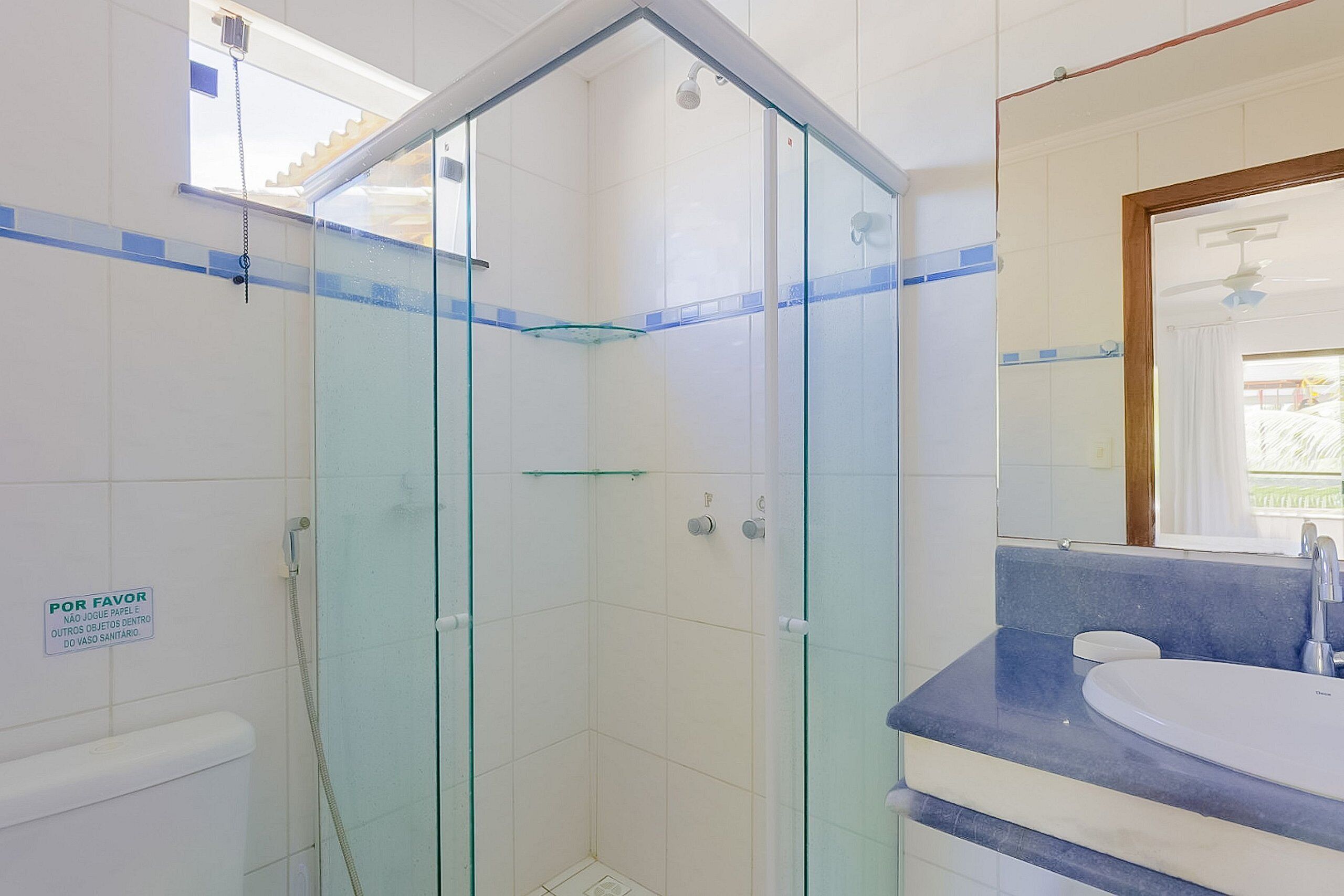 A bathroom with a glass-enclosed shower, a sink, and a mirror.