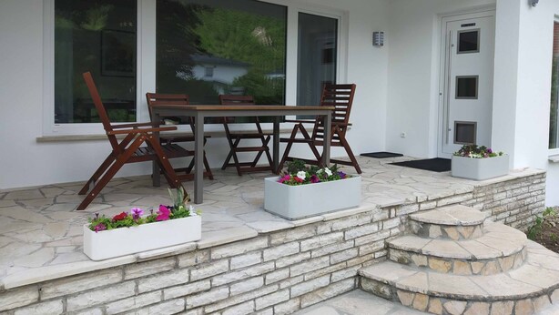 Une terrasse avec une table et des chaises, des marches en pierre et des jardinières.