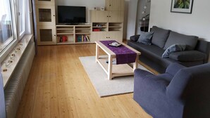Un salon équipé d’un téléviseur, de meubles en bois, d’un canapé et d’une table basse.