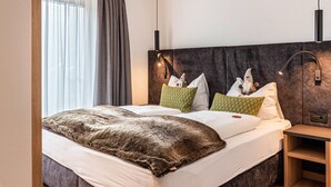 Un letto matrimoniale con coperta marrone, una testiera con luci a parete e un comodino con lampada.