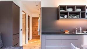 Una cucina moderna con mobili grigi, una mensola a incasso con stoviglie e un pavimento in legno.