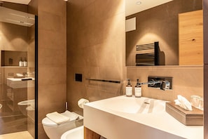 A modern bathroom with a glass shower enclosure, a white sink with a large mirror, and a wooden vanity.
