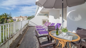 A balcony with sun loungers, a table with a bottle and glasses, and a large umbrella. - Holiday Apartment 'Apartment at Clube Praia da Oura' with Sea View (Albufeira)