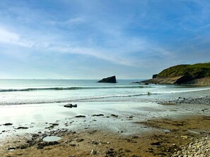 A beach with rocky terrain, calm water, and a distant rocky outcrop. - Lavender - Luxurious Barn Conversion (Haverfordwest)