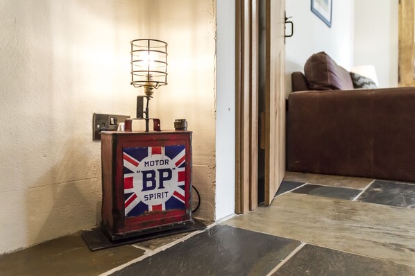 A vintage BP Spirit gas pump in a hallway with a brown leather sofa and a lamp in the background. - Lavender - Luxurious Barn Conversion (Haverfordwest)