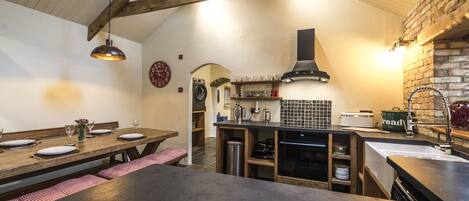 Une cuisine rustique avec une table en bois dressée pour le repas, un mur en briques et un four moderne.