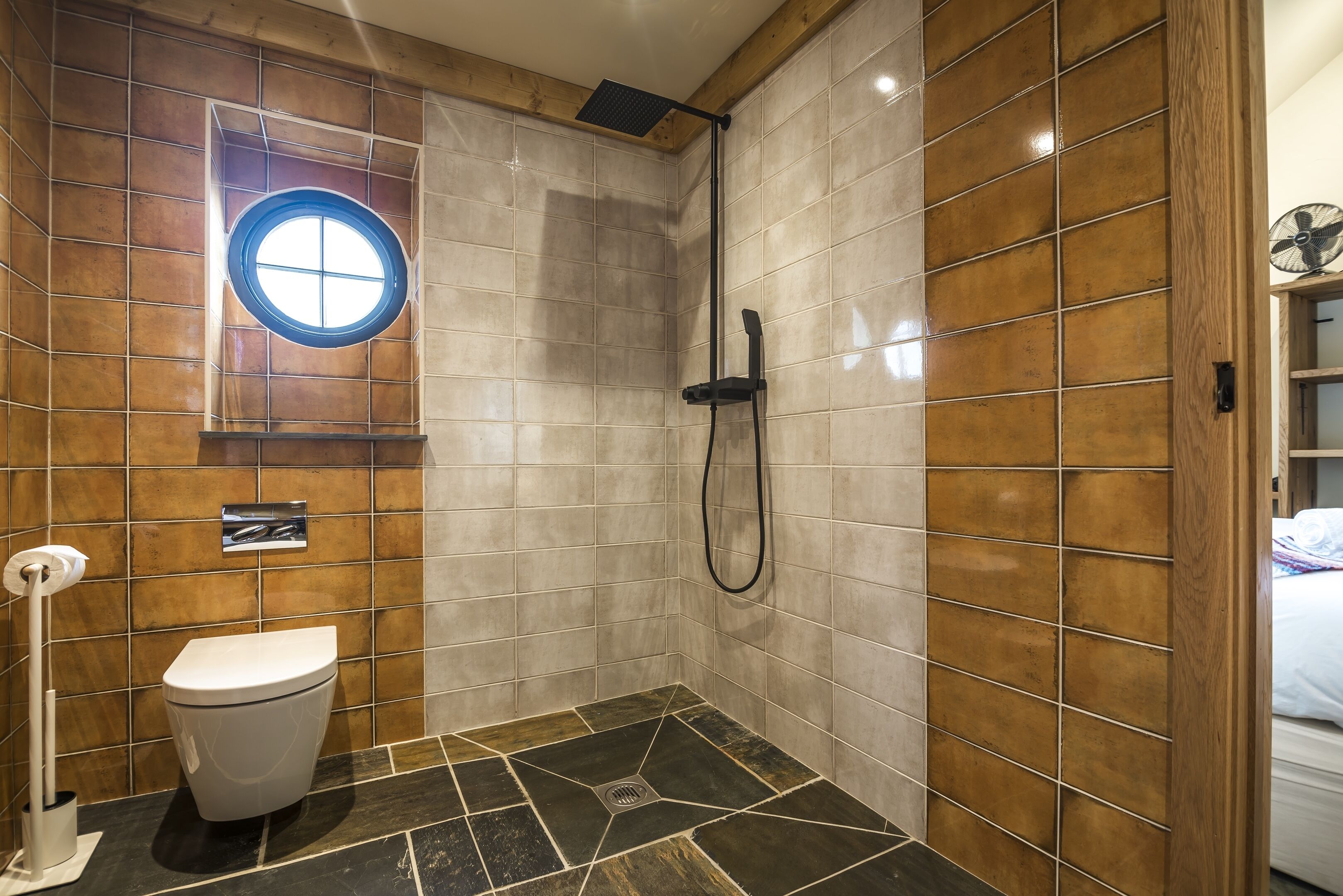 A bathroom with a shower, toilet, and a window.