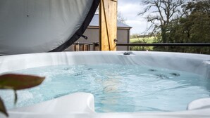 A hot tub with a white cover, a wooden structure in the background, and a leaf in the foreground.