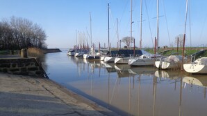 Un puerto deportivo con varios veleros amarrados a lo largo de una vía fluvial tranquila.