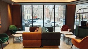 A modern interior with a sofa set, two round tables, and green chairs. - Orange Hotel (Tianjin Wudadao) (Tianjin)