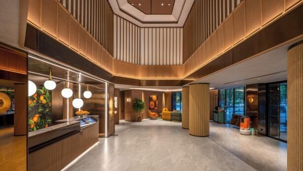 A modern lobby with a reception desk, pendant lighting, and a central plant. - Orange Hotel (Tianjin Wudadao) (Tianjin)