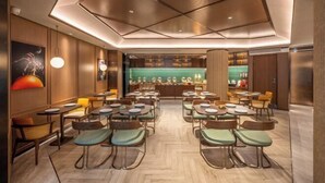 A modern restaurant with a central bar area, multiple dining tables, and chairs arranged in a spacious layout. - Orange Hotel (Tianjin Wudadao) (Tianjin)