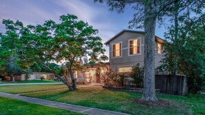 Uma casa de dois andares com um gramado bem cuidado e uma árvore no jardim frontal.
