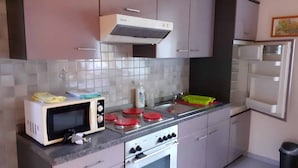 Cocina compacta con microondas, estufa y lavaplatos.