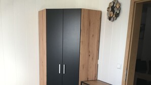 A bedroom with a bed, a wardrobe, and a small table. - Ferienwohnung Heigemeir (Ehekirchen)