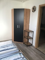 Um quarto com uma cama, um guarda-roupa e uma mesinha.