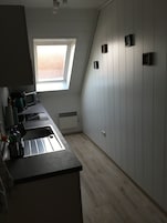 Uma cozinha compacta com janela, micro-ondas e pia.