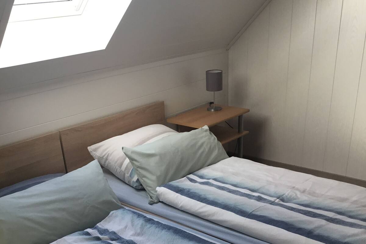 A bedroom with two beds, a nightstand, and a lamp.