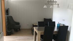 A dining area with a wooden table and chairs, a ceiling light fixture, and a potted plant. - Ferienwohnung Heigemeir (Ehekirchen)