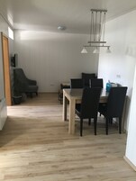 Uma sala de jantar com uma mesa e cadeiras de madeira, um lustre e um vaso com planta.