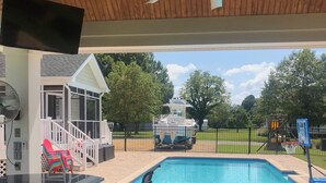 A covered outdoor area with a pool, seating, and a boat dock. - Coco’s Cabana (Deltaville)