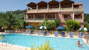 A hotel with a swimming pool, multiple balconies, and outdoor seating areas. - Anemomylos Studios (Zakynthos)