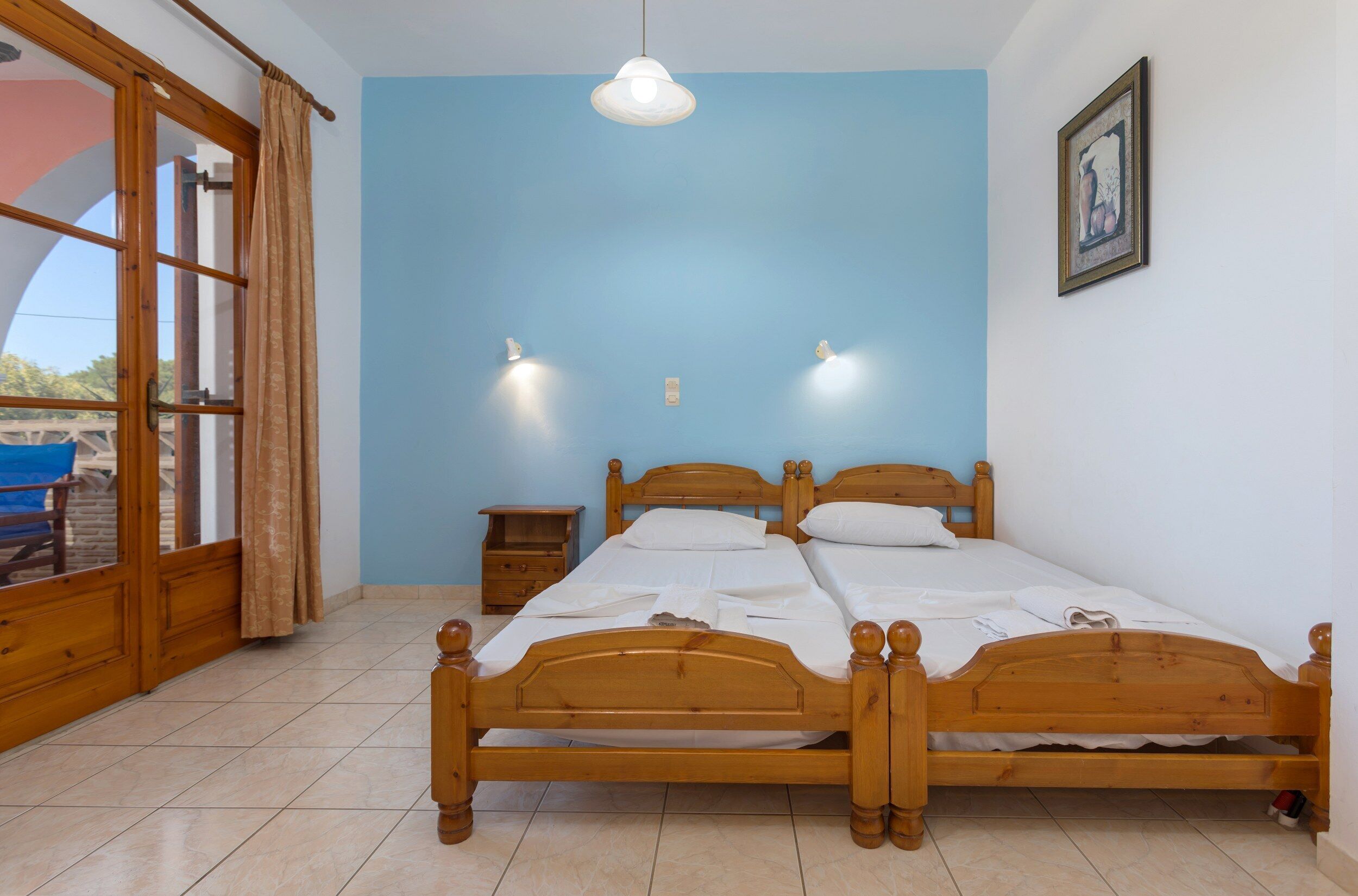 A bedroom with a wooden bed, two bedside tables, a nightstand, and a window with curtains.
