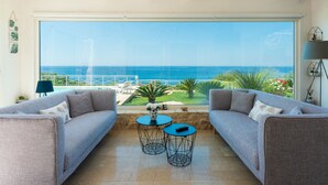 Un balcon avec vue sur la mer, deux canapés gris, une petite table ronde et une lampe.
