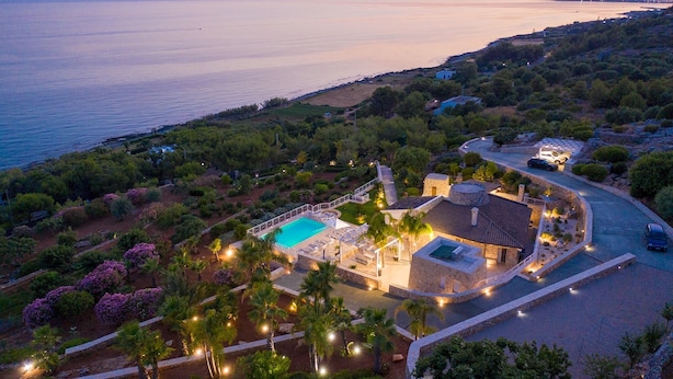 Une villa avec piscine, entourée d’une végétation luxuriante et offrant une vue sur la mer.