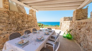 A table set for six with a view of the sea, stone walls, and a pergola overhead. - Tenuta Scialandre 10, Emma Villas (Patù)