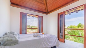 Ein Schlafzimmer mit einem Bett, einem Fenster und Blick ins Grüne.