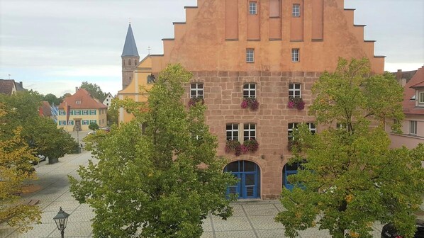 Historiallinen rakennus, jossa on huomiota herättävä torni, puita sisältävä sisäpiha ja sininen sisäänkäynti.