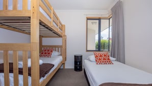 A room with two bunk beds, a small trash bin, and a window with curtains. - Mountain Views from Meadowstone (Wānaka)
