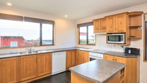 A modern kitchen with wooden cabinets, a built-in microwave, and a granite countertop. - Mountain Views from Meadowstone (Wānaka)