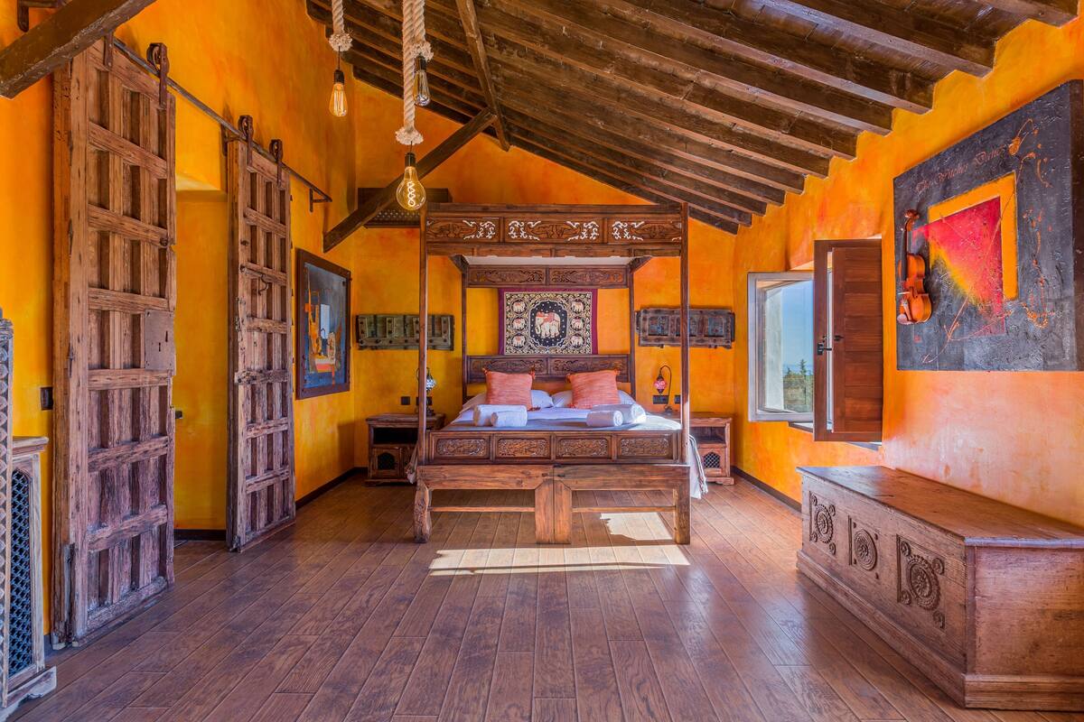 Une chambre dotée d’un lit à baldaquin, de murs en bois et d’un plafond rustique.