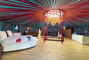 Een ruime, goed verlichte kamer met een groot bed, een houten bureau en een hangende lamp.