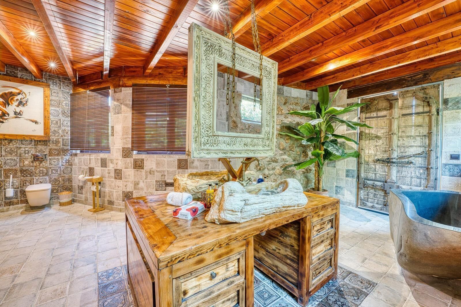 A rustic bathroom with a wooden vanity, a hanging mirror, and a bathtub.