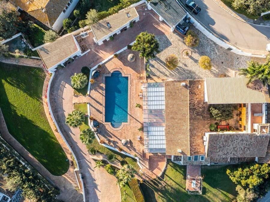 Vista aérea de una propiedad residencial con piscina, terraza cubierta y jardín bien cuidado.