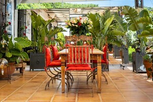 Eine Terrassengaststätte mit einem Holztisch und -stühlen, umgeben von Kübelpflanzen und einem Zierzaun.