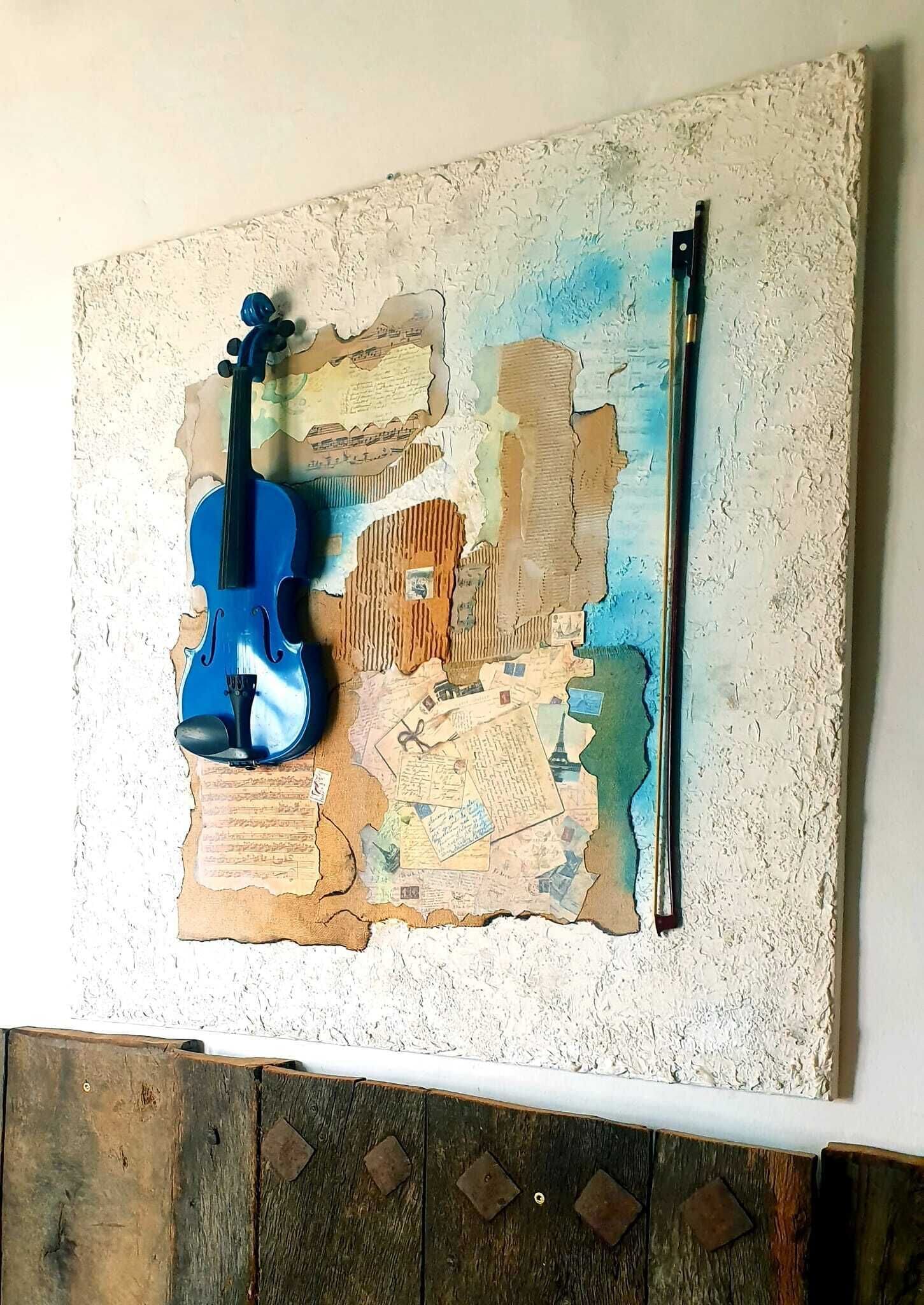 Una obra de arte mural con un violín y un arco sobre una superficie texturizada.