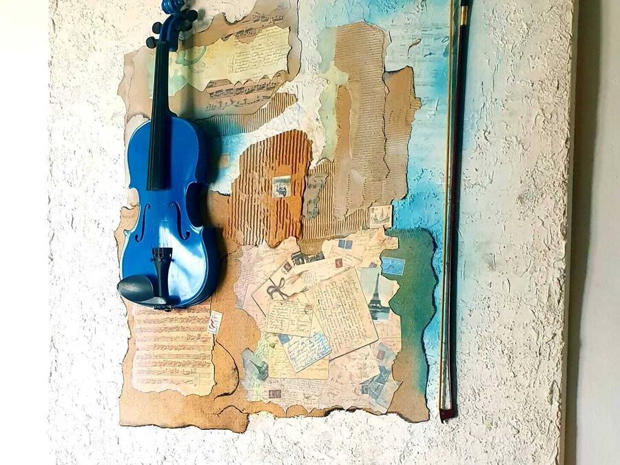 Una obra de arte mural con un violín y un arco sobre una superficie texturizada.
