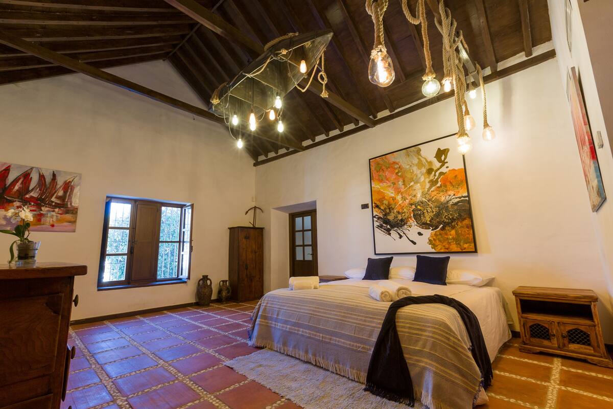 Une chambre à coucher avec un grand lit, une fenêtre et un luminaire au plafond.