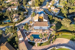 Μια αεροφωτογραφία μιας οικιστικής περιοχής με πολλά σπίτια, μια πισίνα και έναν καλά περιποιημένο κήπο.