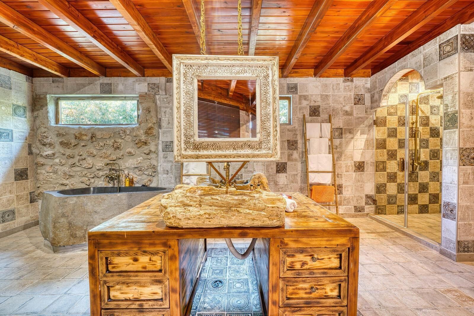 A stone-walled bathroom with a wooden vanity, a large mirror, and a shower area.