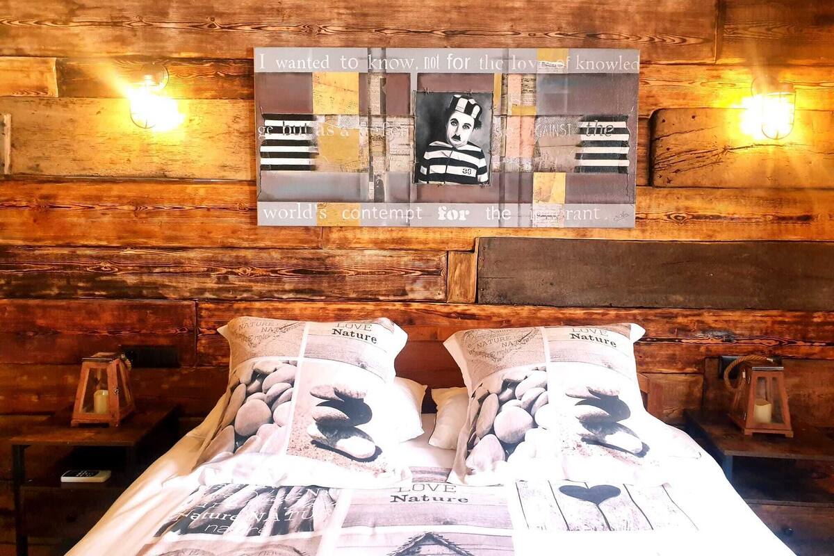 Un lit avec une tête de lit en bois et un mur orné d’une citation et d’un tableau encadré.