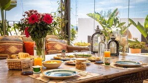 Une table de petit-déjeuner avec divers plats, boissons et un vase rempli de fleurs.
