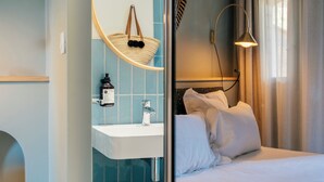 Une chambre d’hôtel avec une salle de bain comprenant un lavabo, un miroir et un porte-serviettes.
