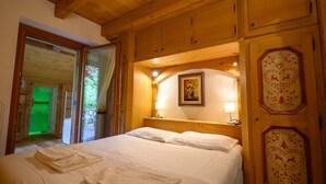 Quarto com painéis de madeira, uma cama, um quadro na parede e uma porta com desenho de coração.