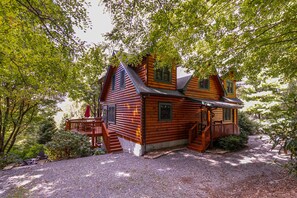 Une cabane en rondins dotée d’un porche et d’un escalier menant à l’entrée.