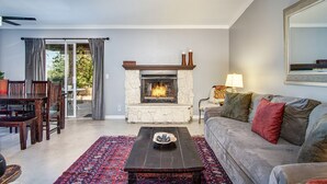 Una sala de estar con chimenea, un sofá, una mesa de centro y un comedor con sillas y una mesa.